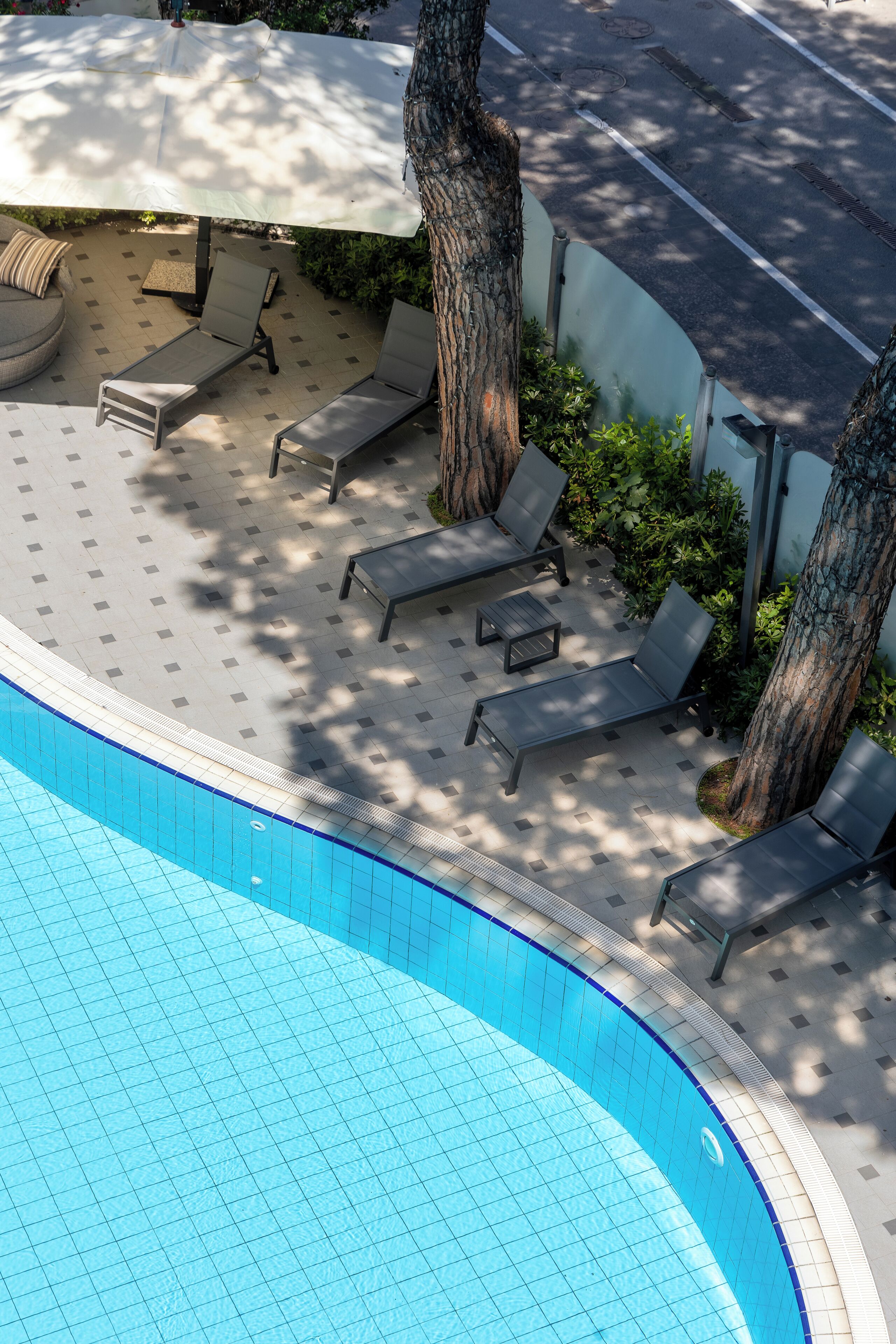 A poolside area with lounge chairs and a large umbrella.