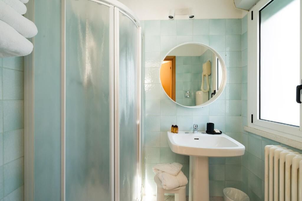 A bathroom with a shower, a sink, and a mirror.