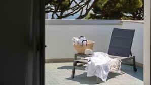 A balcony with a lounge chair, a small table, and a wicker basket with items. - Hotel Adriatica (Riccione)
