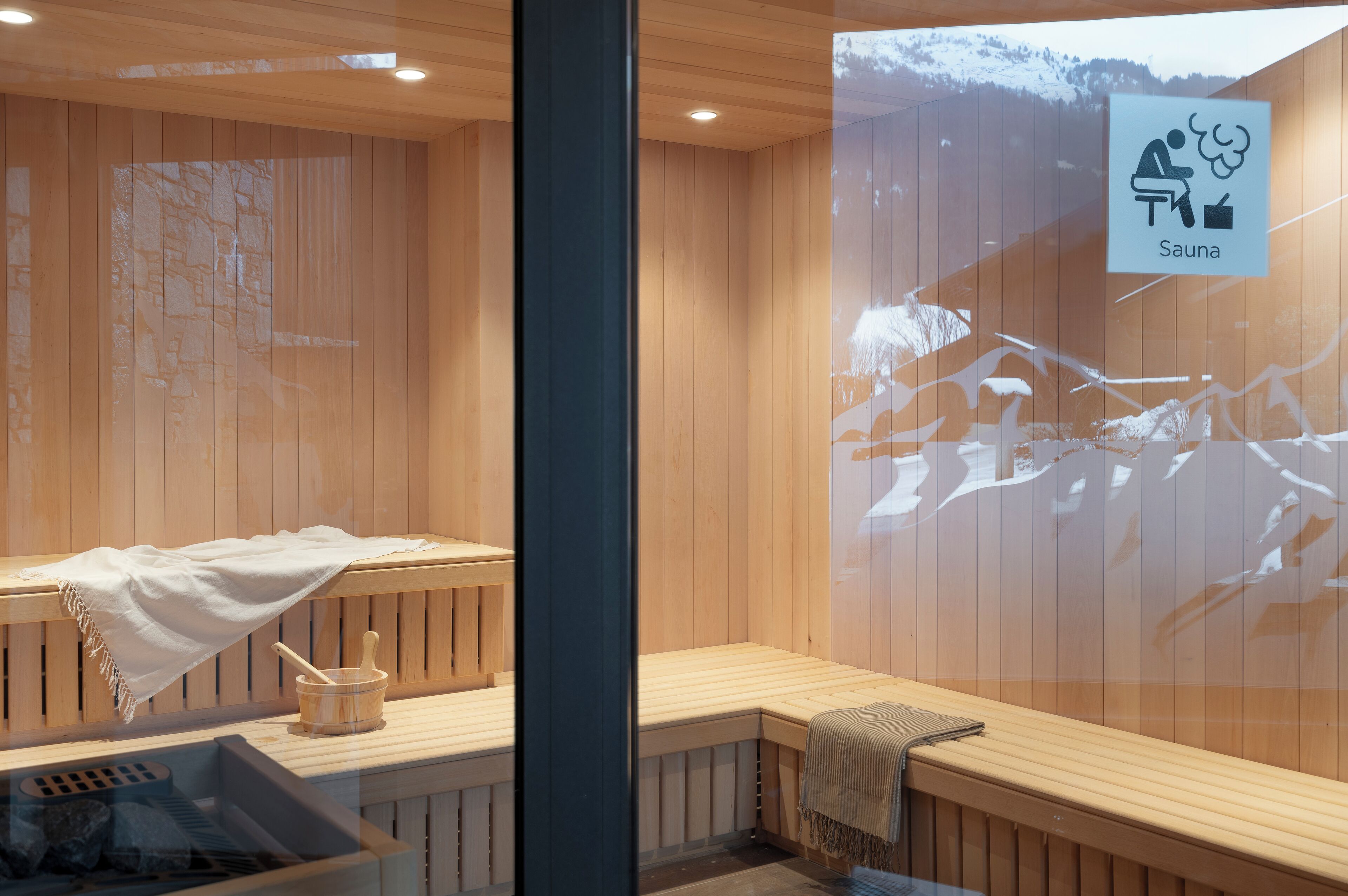 A sauna with wooden benches, a stone wall, and a sign indicating the sauna area.