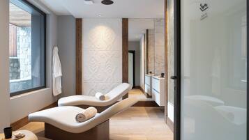 Relax in a serene spa room with a massage table, towel, and large window.