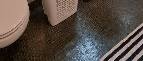 Un baño con inodoro, lavabo, espejo y cesto de ropa.