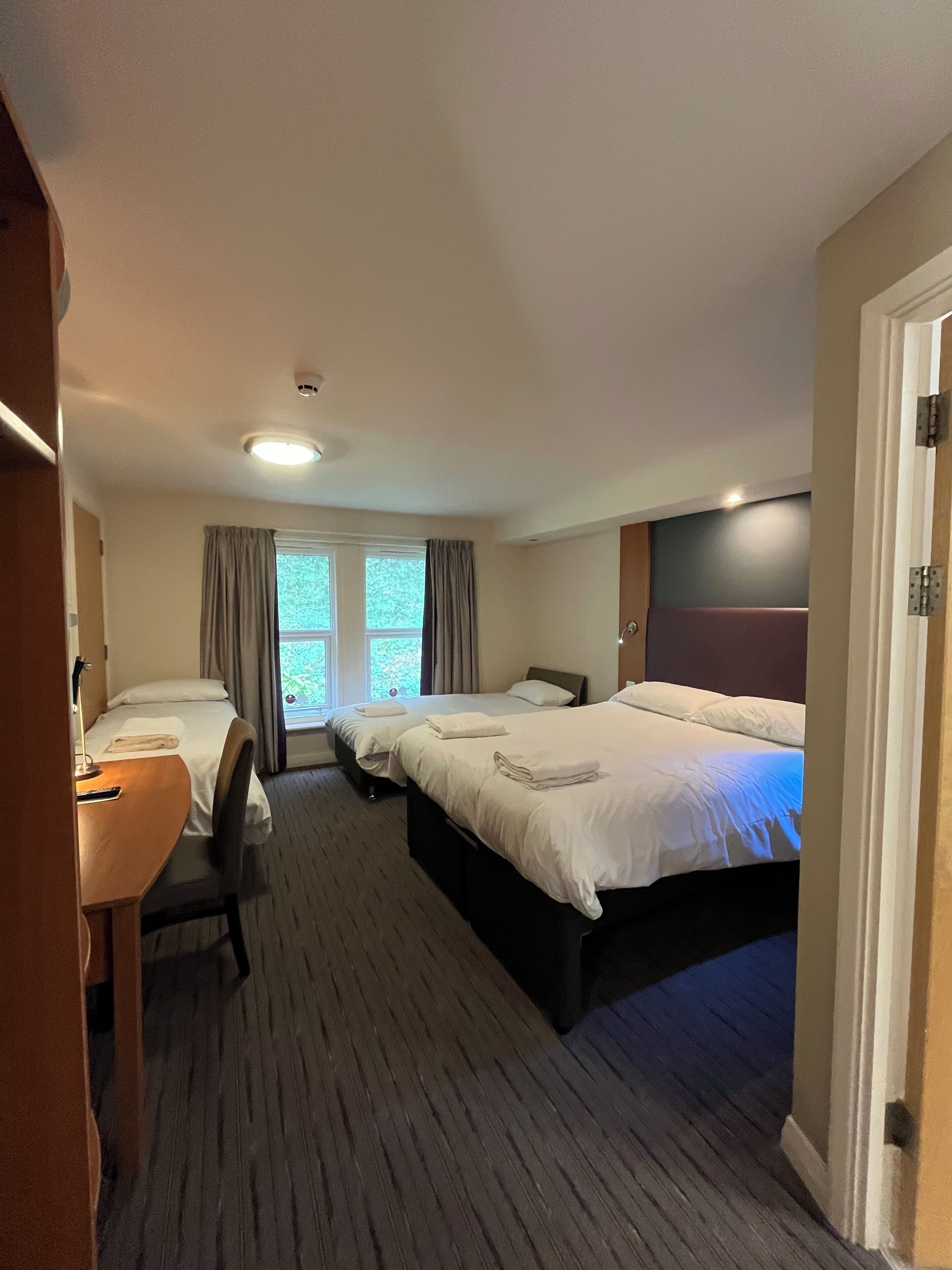 Habitación de hotel con dos camas, un escritorio y una silla.
