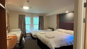Habitación de hotel con dos camas, un escritorio y una silla.