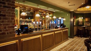 A bar area with a wooden counter, multiple beer taps, and a cash register. - Craigside Manor (Llandudno)