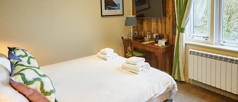 A hotel room with a bed, a desk, a chair, a television, and a window with curtains.