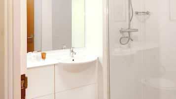A modern bathroom with a glass shower enclosure, a white sink, and a toilet.