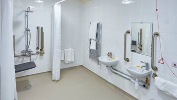 Een moderne badkamer met een douche, twee wasbakken, een toilet en een spiegel.