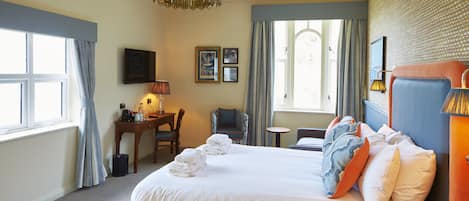 Una camera d'albergo con un letto, una scrivania, una sedia, un tavolino e una finestra con tende.