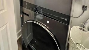Een compacte LG ThinQ wasmachine met een glazen deur, een bedieningspaneel en een voorlader.