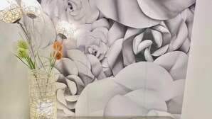 Een eetgedeelte met een tafel, een stoel en een wand met een bloemenmotief.