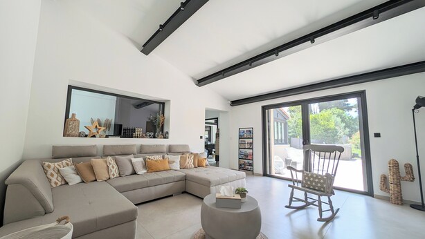 A modern living room with a sectional sofa, a round ottoman, and a rocking chair. - La Bastide des Baux, Saint-Rémy-de-Provence, 6 CHB, 3 SDB, Salt pool 11x4,5 (Saint-Rémy-de-Provence)