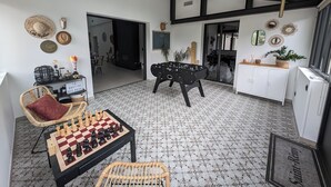 A spacious room with a foosball table, a chessboard, and a wicker chair. - La Bastide des Baux, Saint-Rémy-de-Provence, 6 CHB, 3 SDB, Salt pool 11x4,5 (Saint-Rémy-de-Provence)