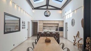 A modern kitchen with wooden cabinets, a dining area with a long table and chairs, and skylights above. - La Bastide des Baux, Saint-Rémy-de-Provence, 6 CHB, 3 SDB, Salt pool 11x4,5 (Saint-Rémy-de-Provence)
