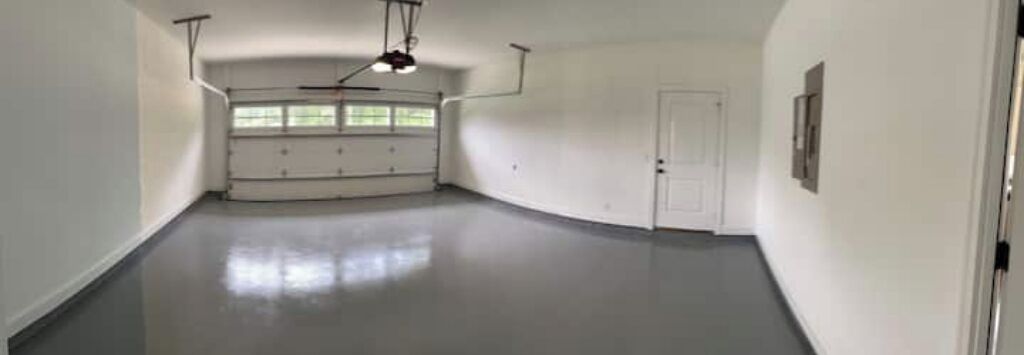 Una habitación amplia y vacía con techo alto, una puerta y un ventanal.