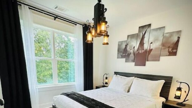 A bedroom with a large bed, a black fur rug, a window with curtains, and wall art.