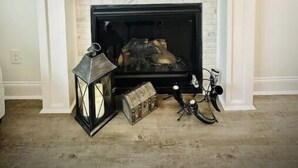 A fireplace with a TV mounted above it, a lantern, and a bicycle.