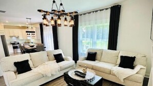 A modern living room with a sofa set, a coffee table, and a chandelier.