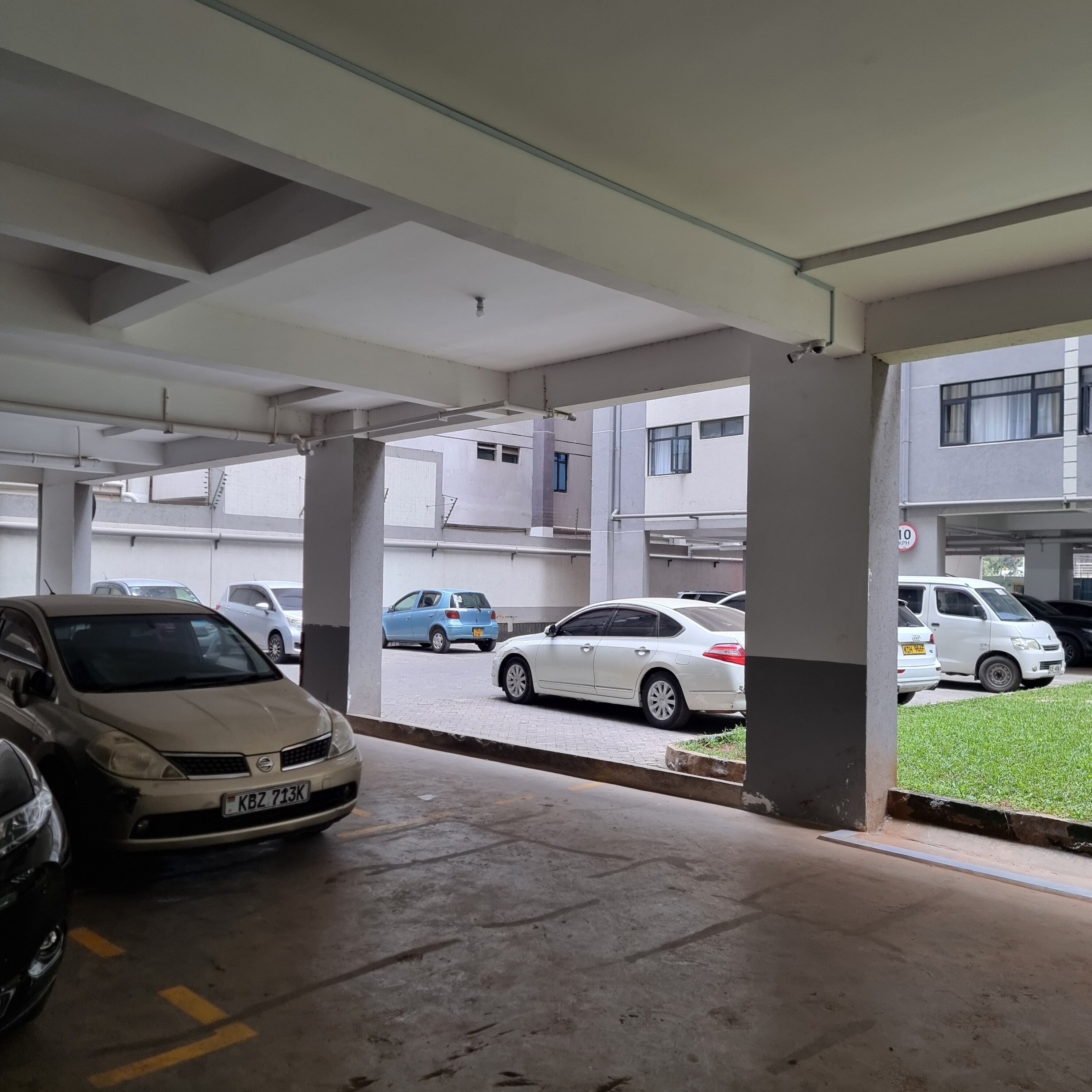 Eine Parkgarage mit mehreren Ebenen, Betonsäulen und einigen parkenden Autos.