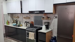 A modern kitchen with a gas stove, oven, refrigerator, and a coffee maker on the countertop. - Serenity Escape in Nairobi City (Nairobi)