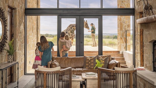 A spacious interior with a large glass door leading to an outdoor area, stone walls, and a modern chandelier. - Longneck Manor (Fredericksburg)