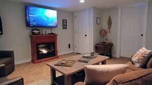Una sala de estar con chimenea, televisor montado en la pared y un sofá.