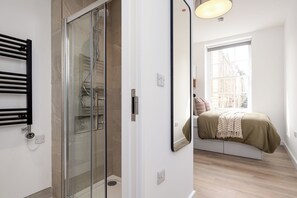A modern bathroom with a glass shower enclosure, a white sink, and a towel rack. - 48 Park Street (Bristol)