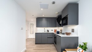 Een moderne keuken met grijze kastjes, een magnetron en een spoelbak.