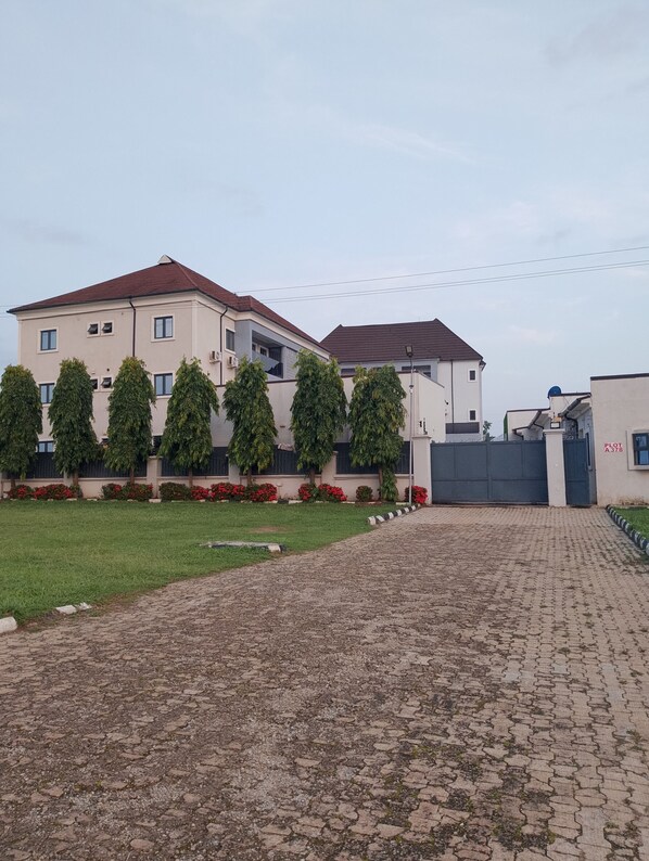 A residential building with a paved driveway and a gated entrance. - Checkers Suit and Apartment (Abuja)