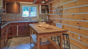 Una cocina con armarios de madera, una isla grande y un ventanal con vistas al verdor.