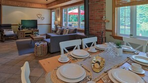 Un comedor con una mesa lista para cuatro personas, un sofá y un televisor al fondo.
