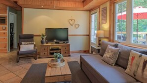 Una sala de estar acogedora con sofá, sillón, mesa de centro de madera y televisor de pantalla plana.
