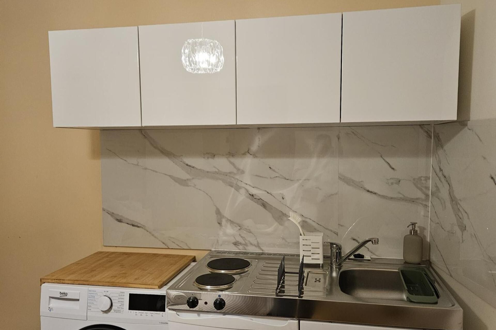 Cocina compacta con lavadora integrada, estufa y lavamanos.