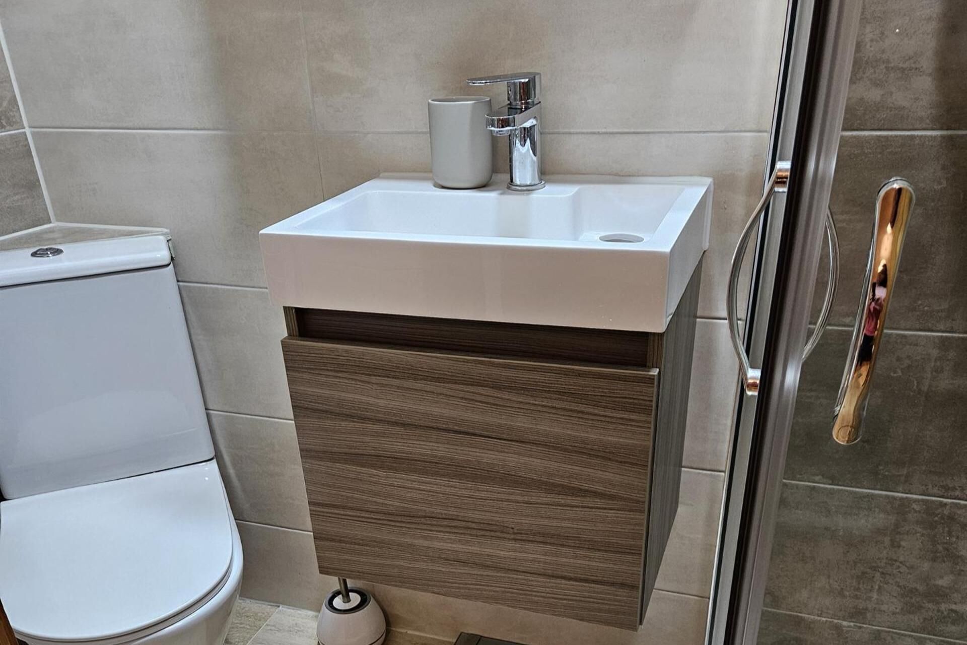 Een badkamer met een wit wastafel, toilet en douchecabine.
