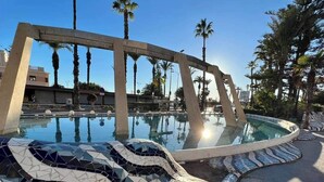 A swimming pool with a mosaic design, surrounded by palm trees and a clear sky. - La casa Divertido (VC)