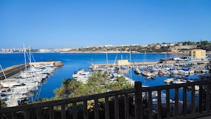 A marina with numerous boats docked, a clear blue sky, and a coastal town in the background. - La casa Divertido (VC)