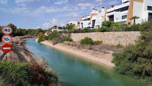 A canal with modern buildings on one side and a stone wall on the other. - La casa Divertido (VC)