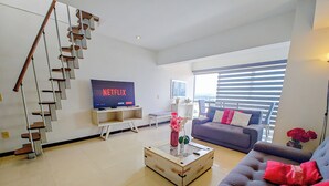 A modern living room with a staircase, a flat-screen TV, a sofa, and a coffee table. - PENTHOUSE SPECTACULAR VIEW OF THE CITY (Guadalajara)