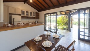 Cuina moderna amb armaris blancs, tauleig de fusta i zona de menjador amb una taula preparada per a quatre.