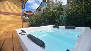 Ein Whirlpool mit Holzterrasse und einer Ziegelwand im Hintergrund.