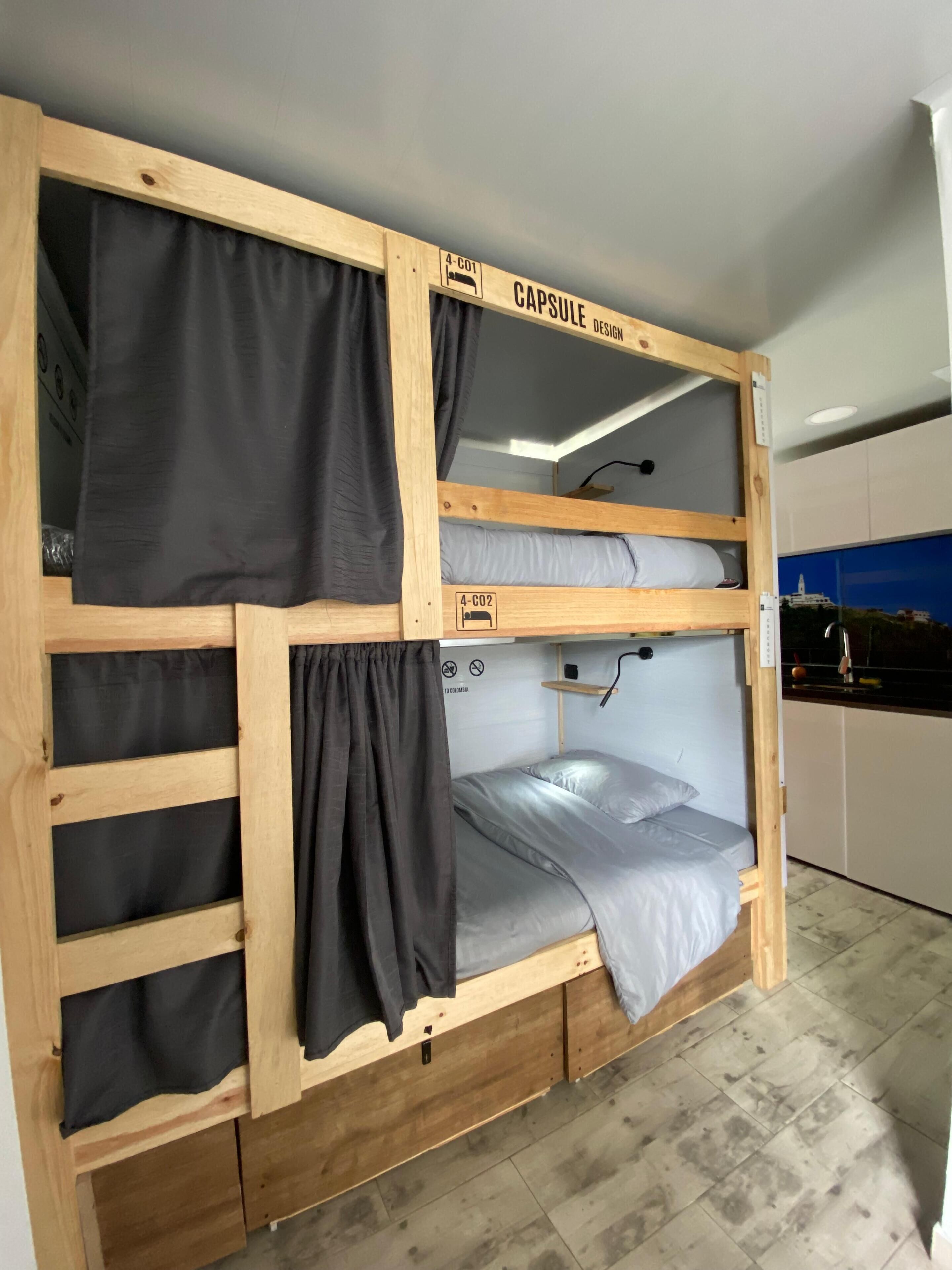 A bunk bed with a capsule design, featuring a lower bunk and a top bunk with a pull-out desk.