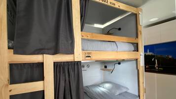 A bunk bed with a capsule design, featuring a lower bunk and a top bunk with a pull-out desk.