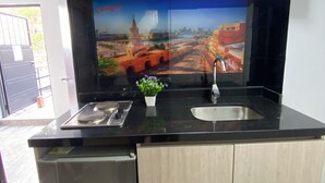 A compact kitchen with a microwave, sink, and a decorative cityscape mural. - Las Aguas Inner Experience (Bogotá)