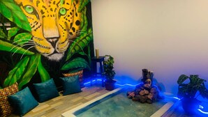 A room with a large leopard mural, a small pool, and various plants. - Las Aguas Inner Experience (Bogotá)