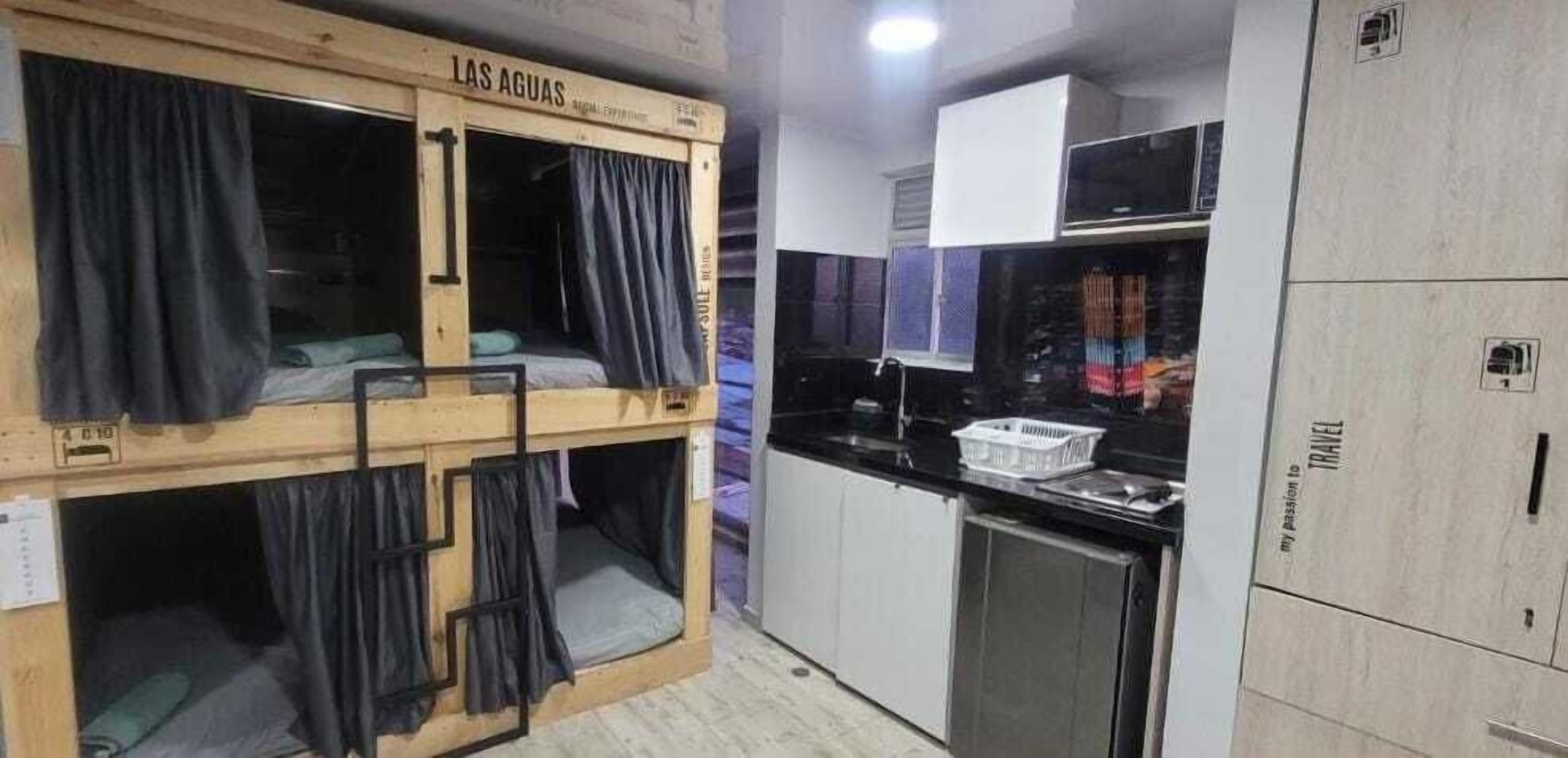 A dorm-style room with bunk beds, a kitchenette, and a small bathroom.
