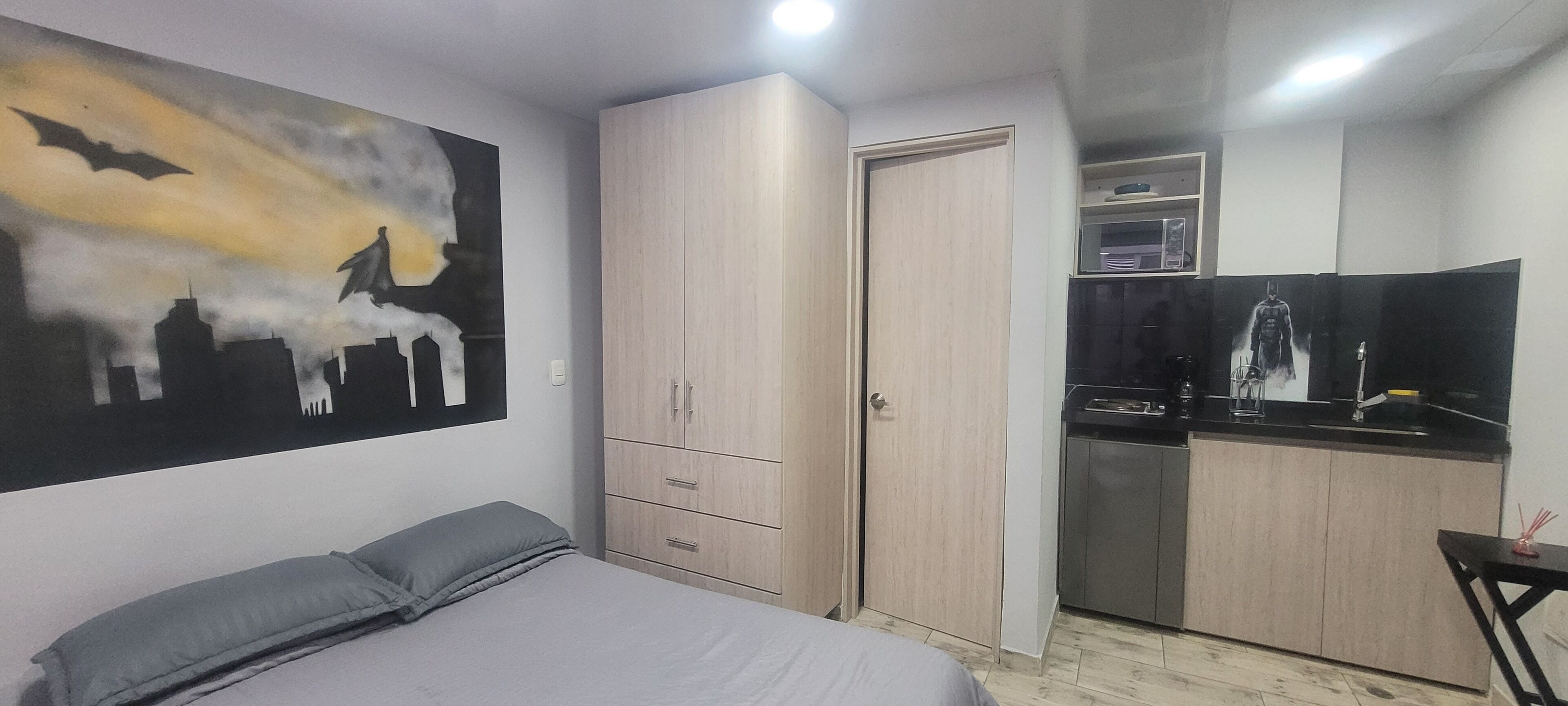 Een slaapkamer met een bed, een kledingkast en een schilderij aan de muur.