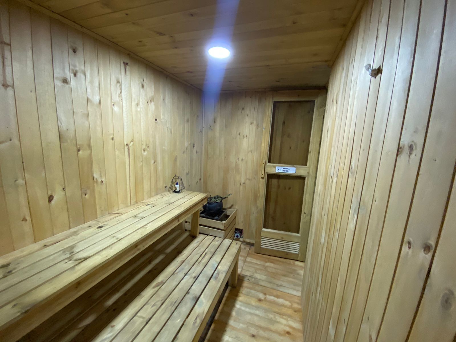 Ein Saunaraum mit Holzbänken, einer Sitzbankheizung und einer Saunatür.