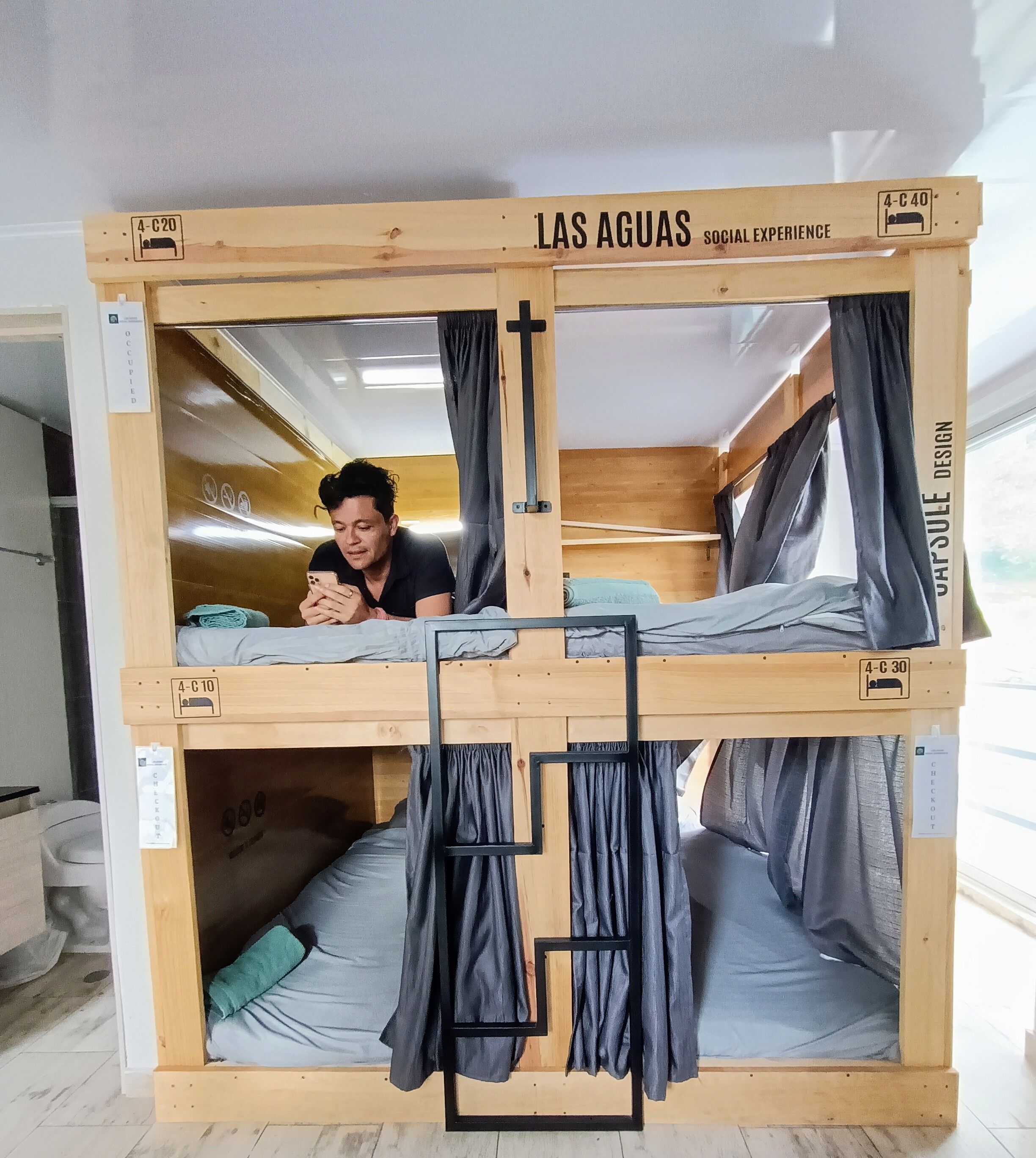 A bunk bed with a sign reading "LAS AGUAS SOCIAL EXPERIENCE" and a checkout sign.