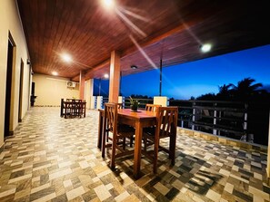 An outdoor patio with a wooden table and chairs, a patterned floor, and a view of the sky at dusk. - Cityscape Yala by 999 Hotel & Restaurant (Tissamaharama)