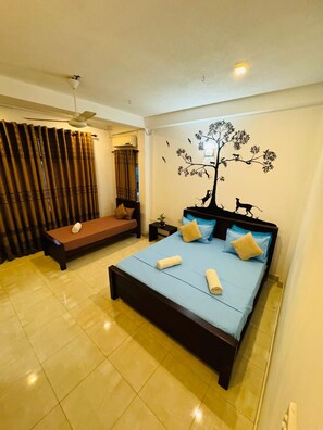 A bedroom with a bed, a bench, a ceiling fan, and a wall mural. - Cityscape Yala by 999 Hotel & Restaurant (Tissamaharama)